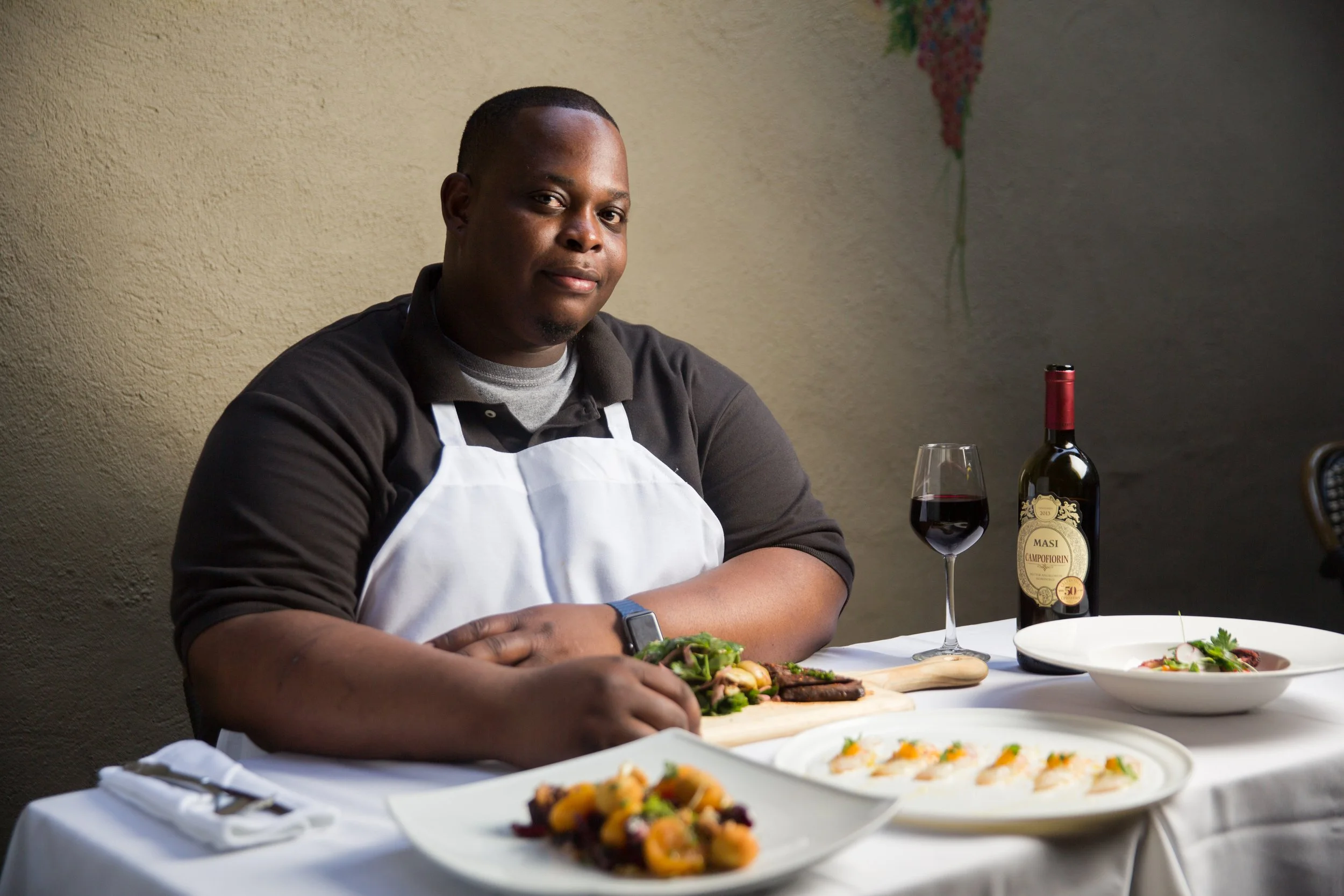 Chef seated at dining table with plated dishes