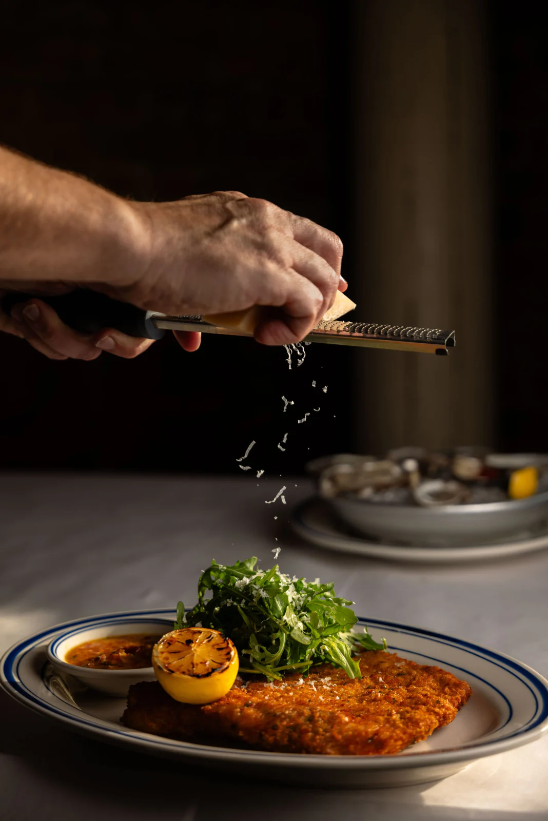 Chef grating cheese over pasta