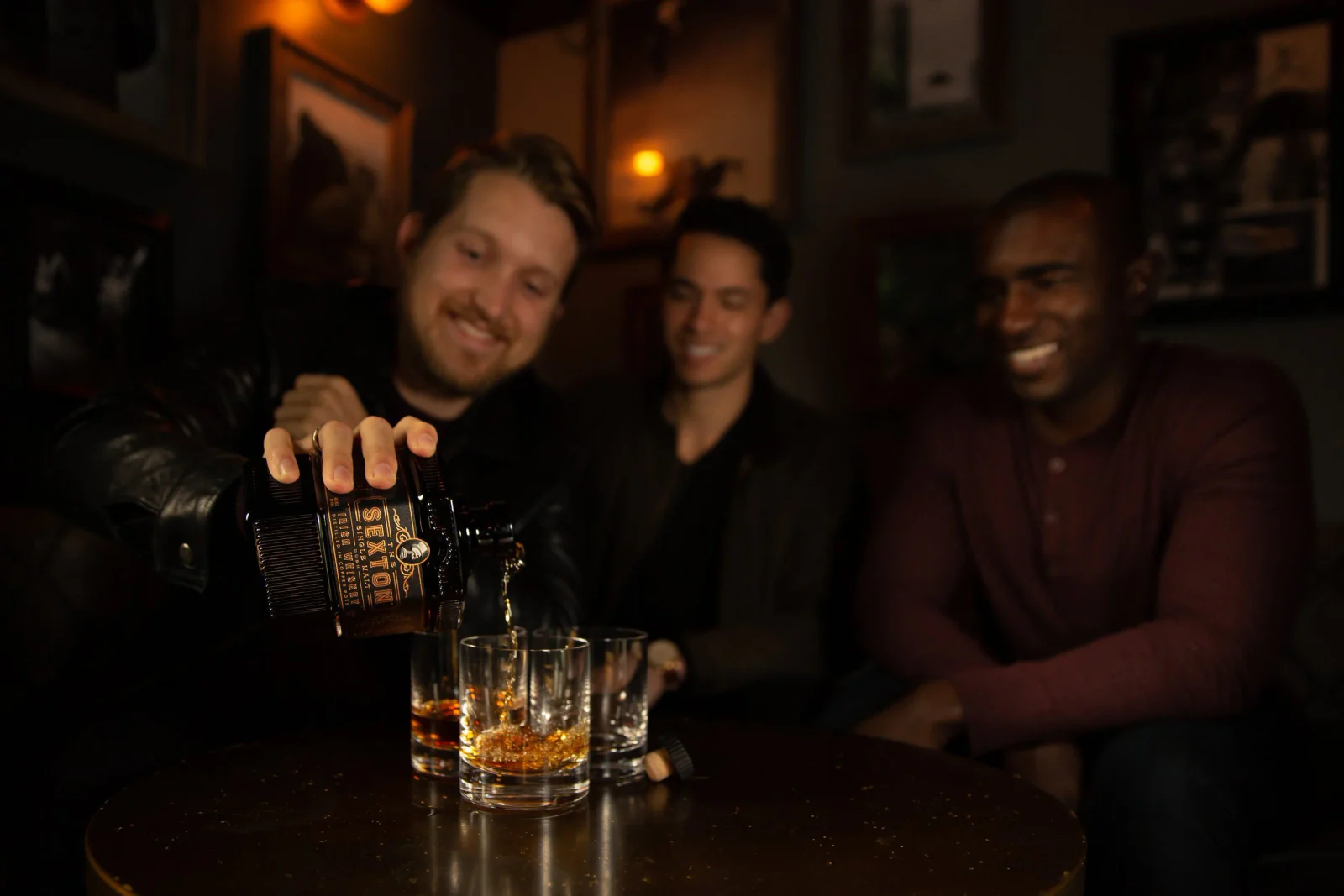Friends gathered around whiskey at a bar